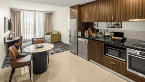 A modern kitchen with a dining area, a refrigerator, a microwave, and a dishwasher. - The Sebel Melbourne Kew (Kew)