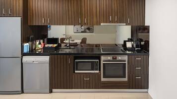 Una cocina moderna con paneles de madera, lavavajillas integrado, microondas, horno y refrigerador de acero inoxidable.