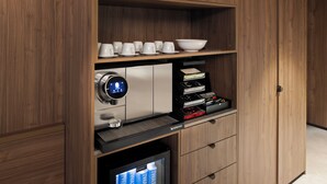 A modern kitchen with wooden cabinetry, a coffee machine, a Nespresso coffee maker, and a built-in TV. - The Sebel Melbourne Kew (Kew)