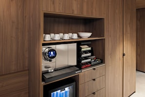 A modern kitchen with wooden cabinetry, a coffee machine, a Nespresso coffee maker, and a built-in TV. - The Sebel Melbourne Kew (Kew)