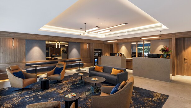 A modern lobby with seating areas, a reception desk, and a kitchen in the background. - The Sebel Melbourne Kew (Kew)