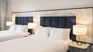 A hotel room with two beds, each with a headboard, bedside lamps, and a large window with curtains. - The Sebel Melbourne Kew (Kew)