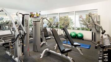 A gym with various exercise equipment, including treadmills, weight machines, and exercise balls.