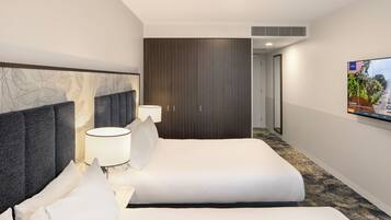 A hotel room with a large bed, a wardrobe, a TV, and a patterned wall.