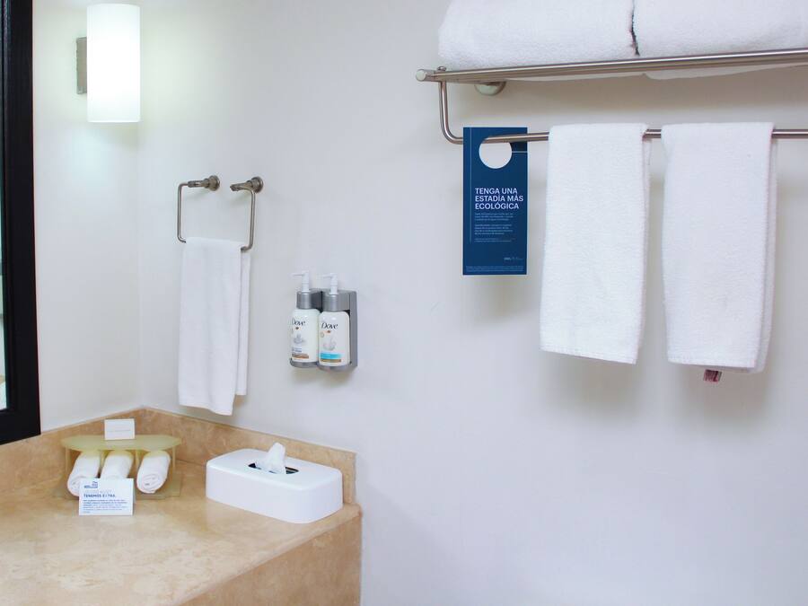 A bathroom with a sink, mirror, towel rack, and toiletries.