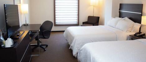 Habitación de hotel con dos camas, un escritorio con computadora, una silla, un televisor y una ventana con persianas.