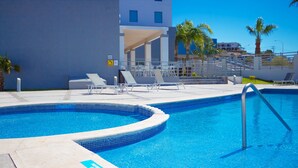Une piscine avec des chaises longues et un espace salon abrité.