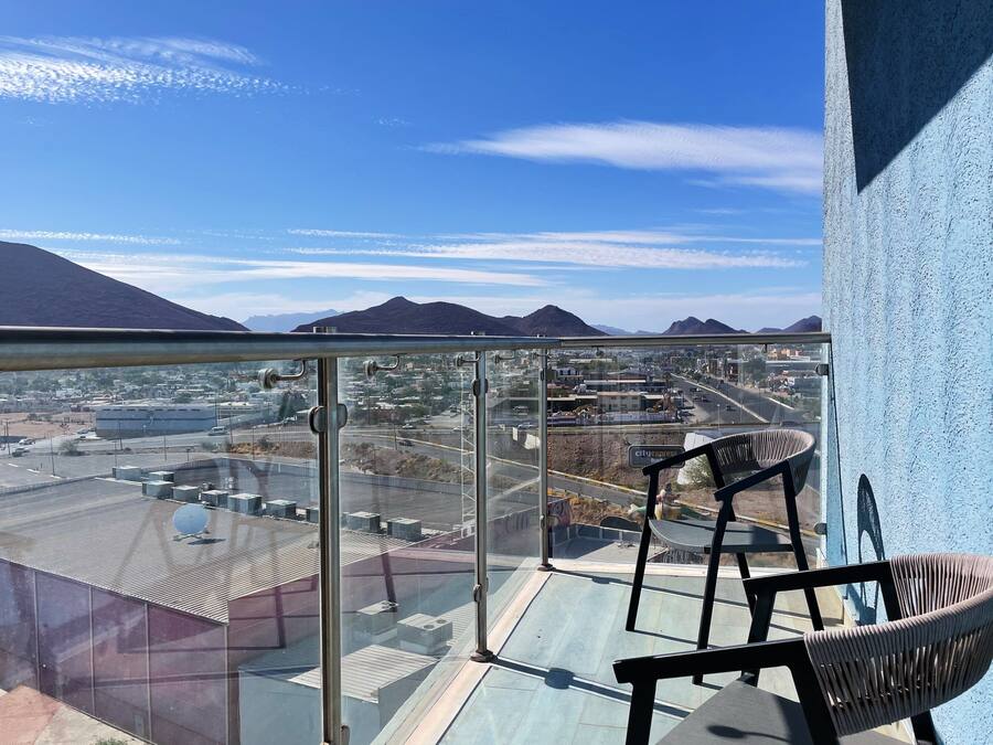 A balcony with a clear view of a cityscape and mountains.