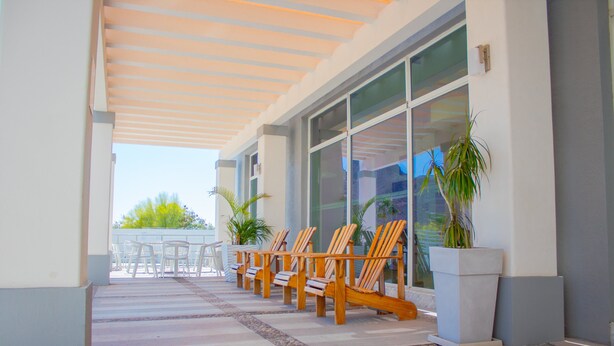 Un espace extérieur aménagé avec des sièges, protégé du soleil et de la pluie, comprenant des chaises en bois et des plantes en pot.