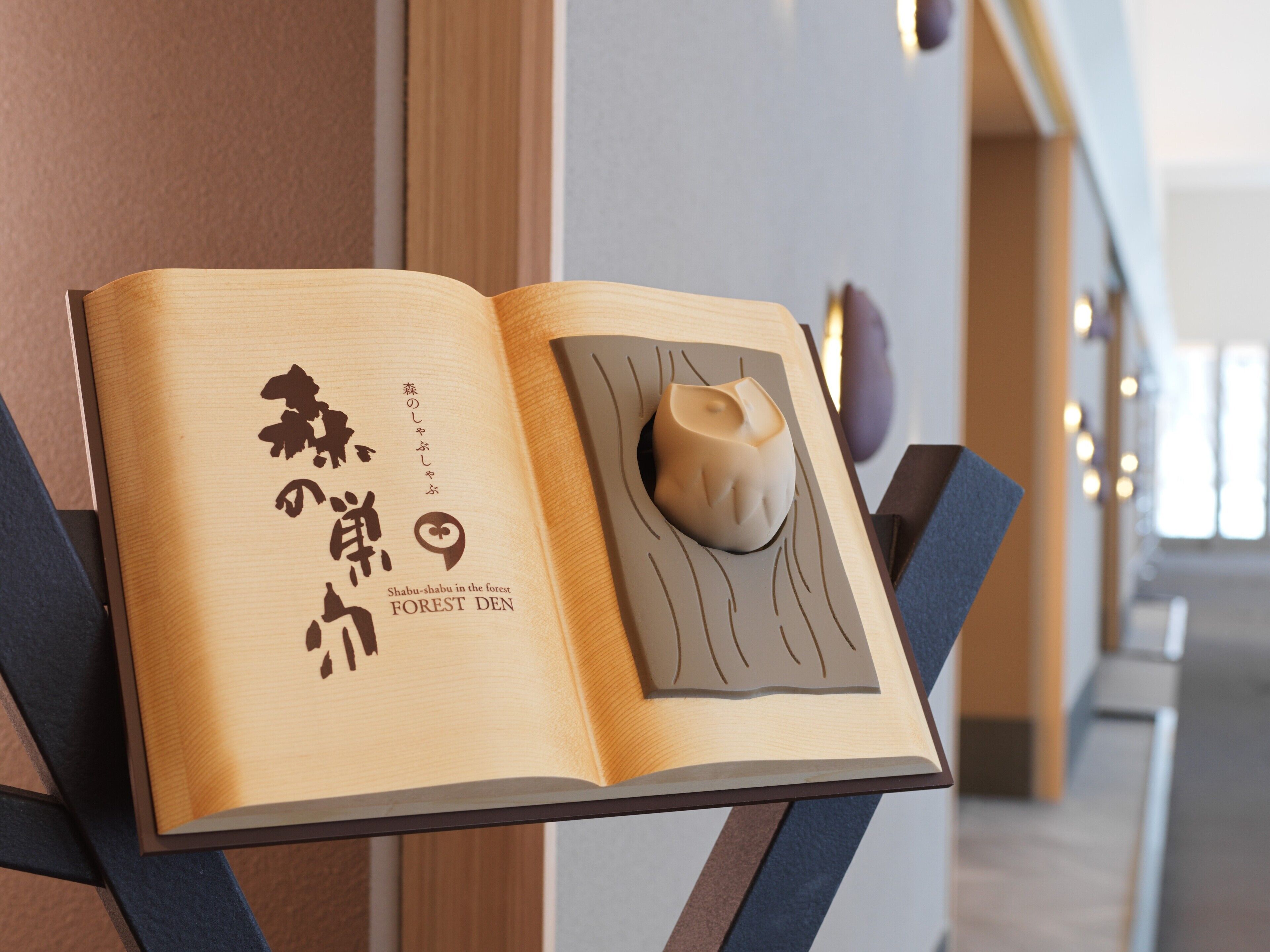 An open book with Japanese text and a wooden sculpture on a stand.