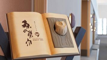 An open book with Japanese text and a wooden sculpture on a stand.