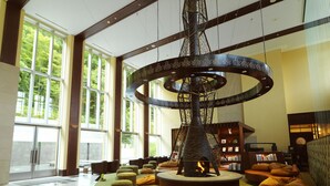 Eine Lobby mit einem zentralen Kamin, Sitzbereichen und einem Bücherregal.