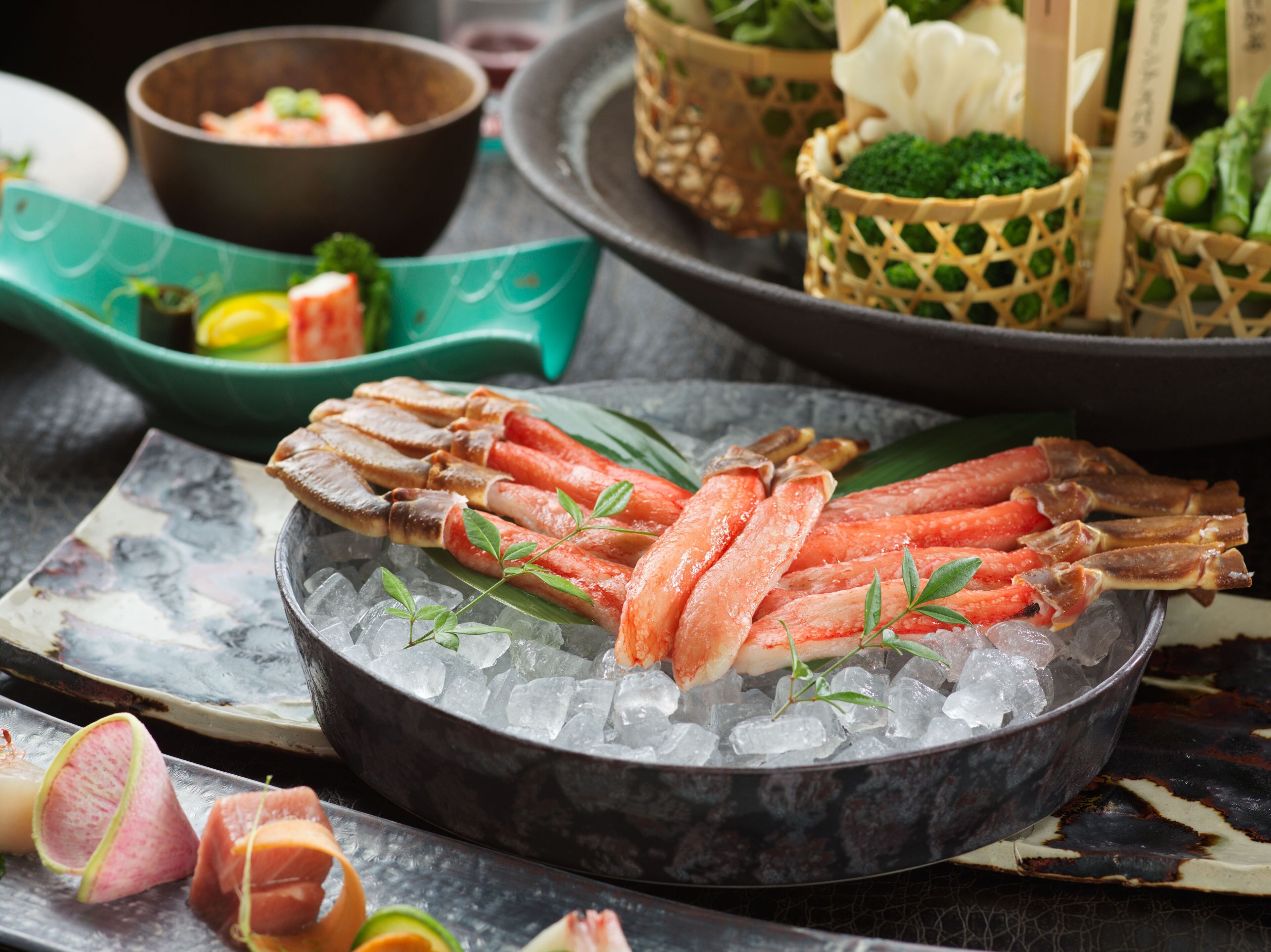 A seafood platter with crab legs on ice, surrounded by various dishes and garnishes.