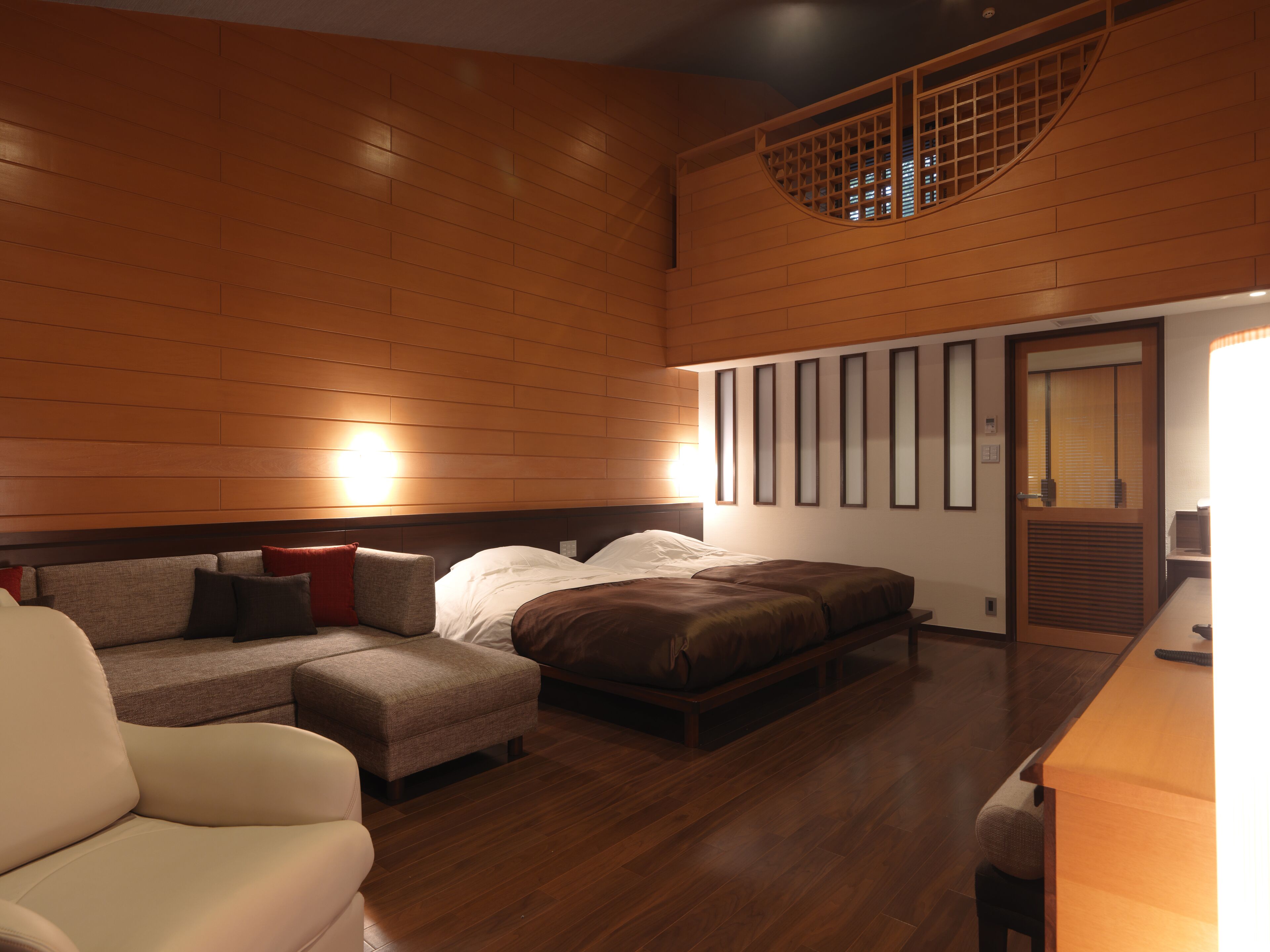 Quarto de hotel com parede de madeira, sofá, cama e uma pequena mesa.