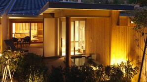 Ein modernes Gebäude mit Holzfassade, einem glasgeschlossenen Raum und einer Terrassenfläche mit Stühlen und Tisch.
