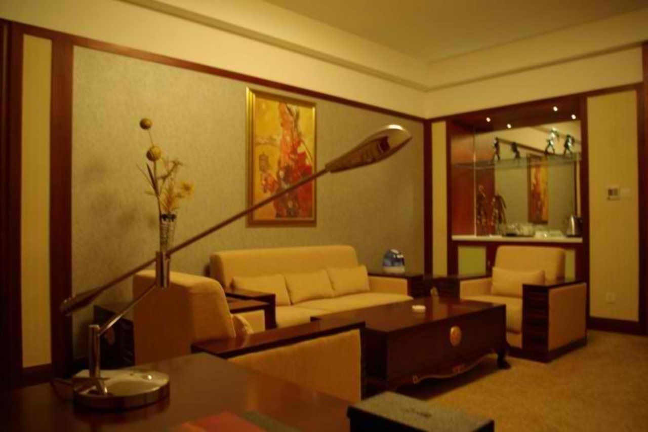 A hotel room with a sofa, a coffee table, a lamp, and a painting on the wall.