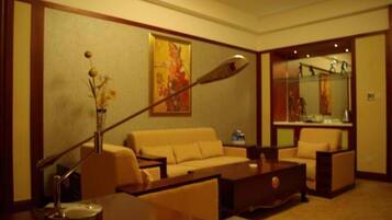 A hotel room with a sofa, a coffee table, a lamp, and a painting on the wall.