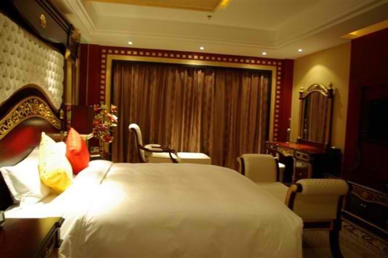 A hotel room with a large bed, a desk, a chair, a dresser, and a mirror.
