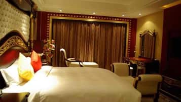 A hotel room with a large bed, a desk, a chair, a dresser, and a mirror.