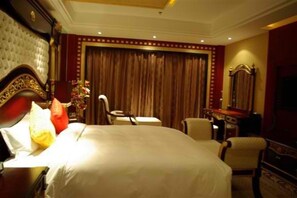 A hotel room with a large bed, a desk, a chair, a dresser, and a mirror.