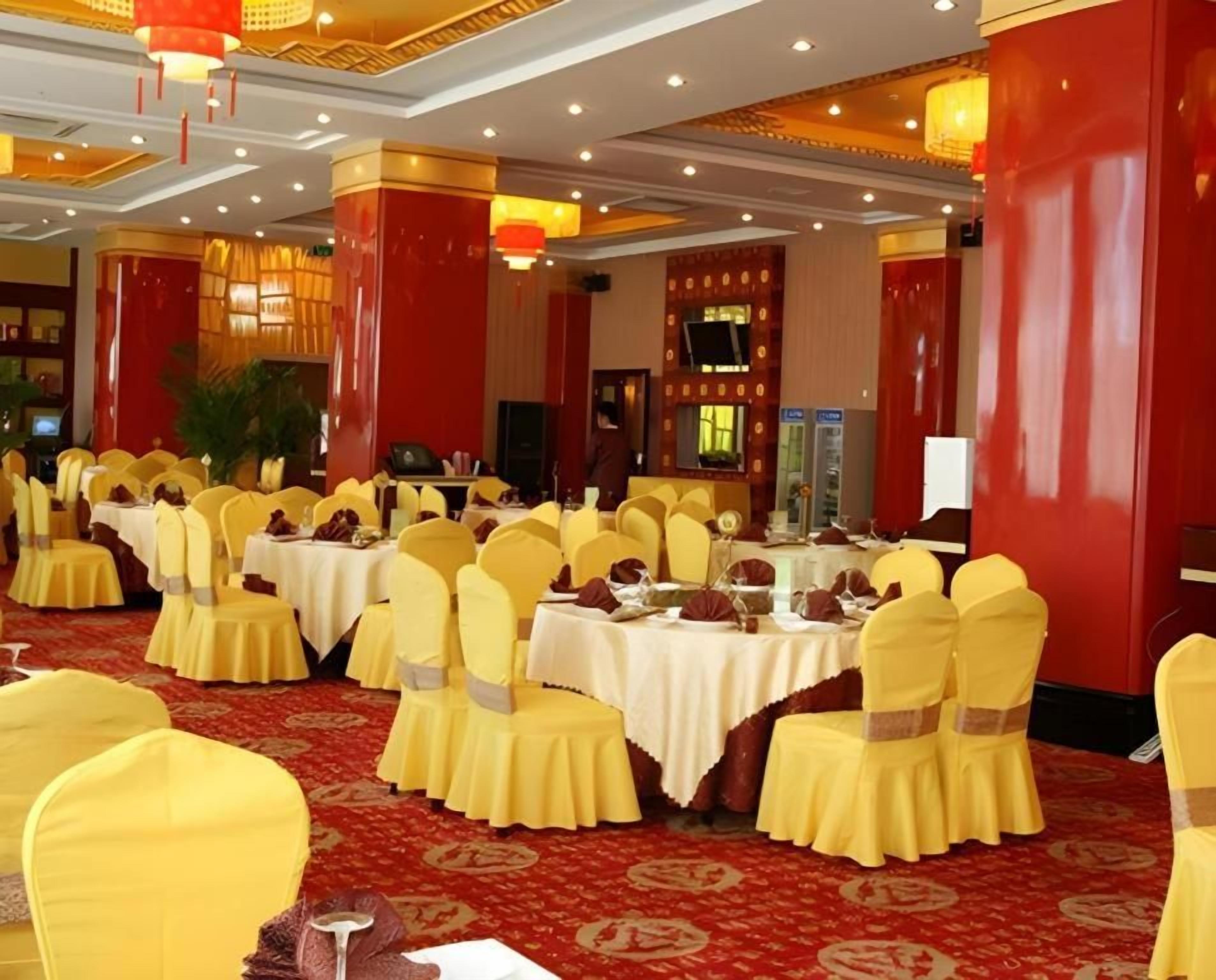 A banquet hall with round tables, yellow chairs, and red accents.
