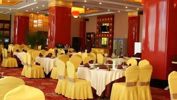 A banquet hall with round tables, yellow chairs, and red accents.