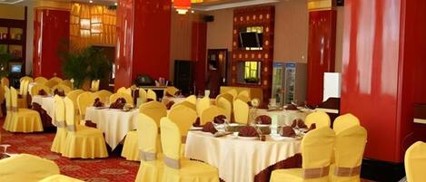 A banquet hall with round tables, yellow chairs, and red accents.