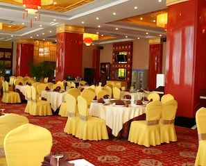 Une salle de banquet avec des tables rondes, des chaises jaunes et des touches de rouge.