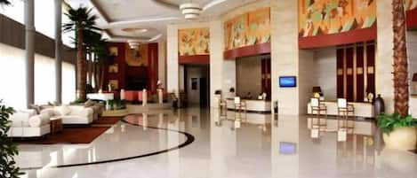 A hotel lobby with a reception desk, seating area, and a large mural.