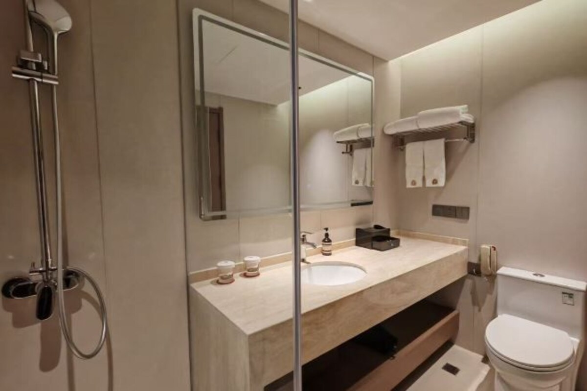 Un baño moderno con mampara de vidrio, lavamanos, inodoro y ducha.