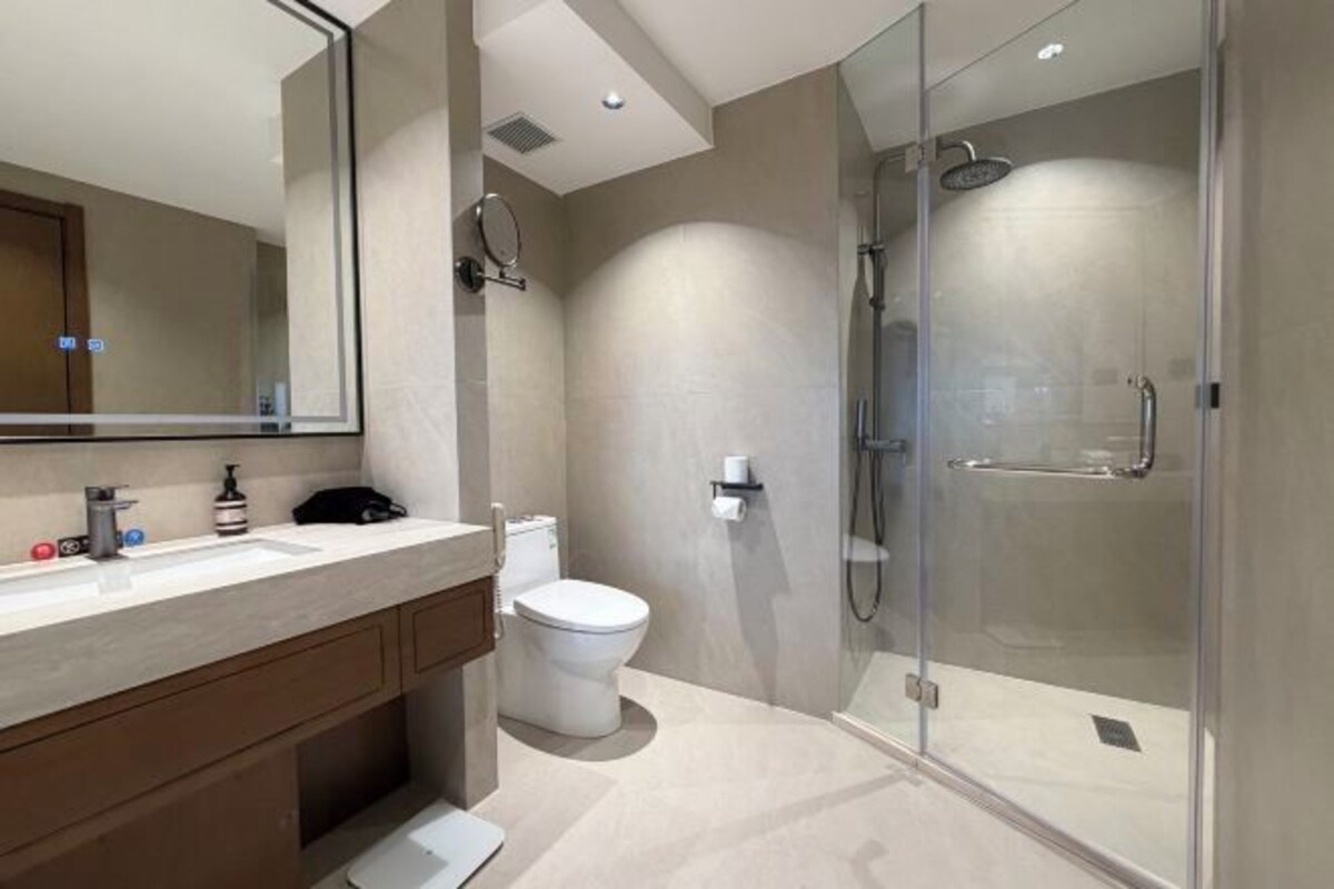 Un baño moderno con cabina de ducha de vidrio, inodoro y tocador con espejo.