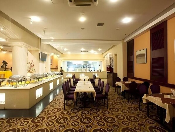 Un comedor de hotel con una mesa larga, sillas y una barra de buffet.