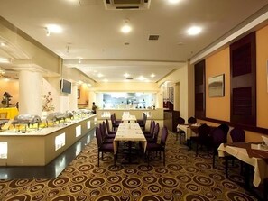 Un comedor de hotel con una mesa larga, sillas y una barra de buffet.