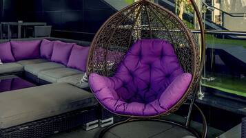 Un espace extérieur moderne aménagé avec des sièges, comprenant un fauteuil suspendu et un canapé.