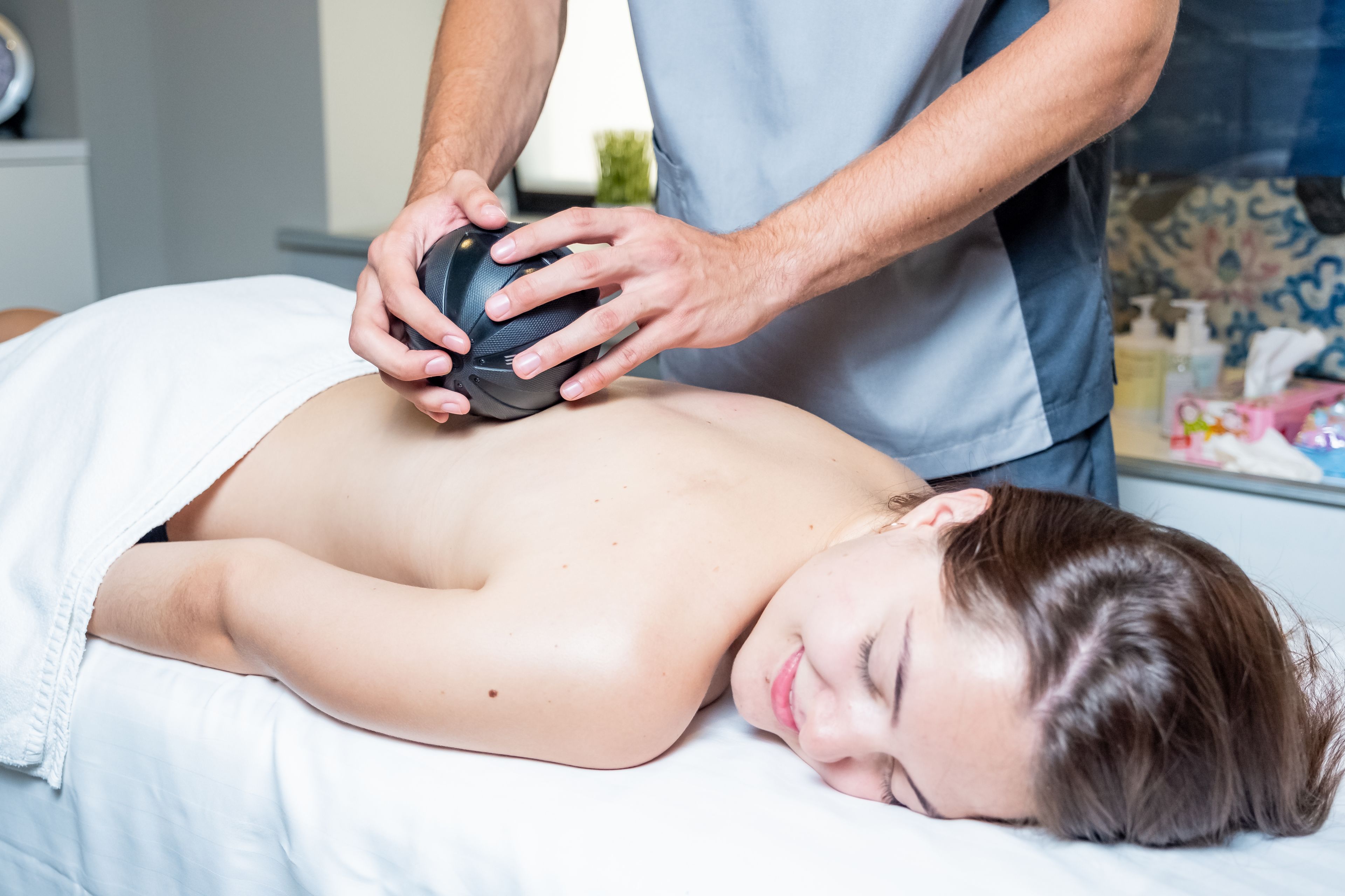 A person lying on a bed receiving a massage.