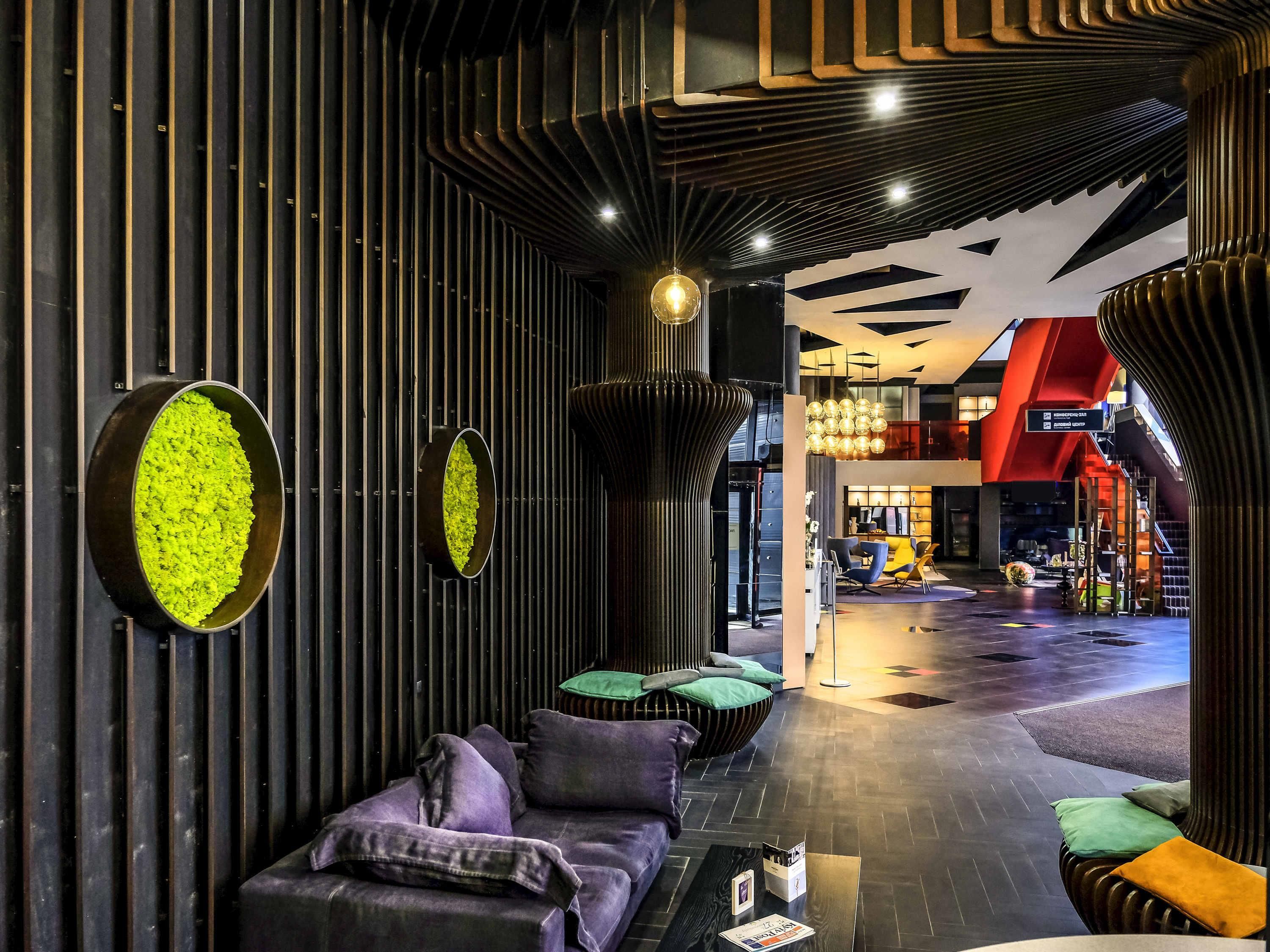 A modern interior with a seating area, a reception desk, and a staircase leading to an upper level.
