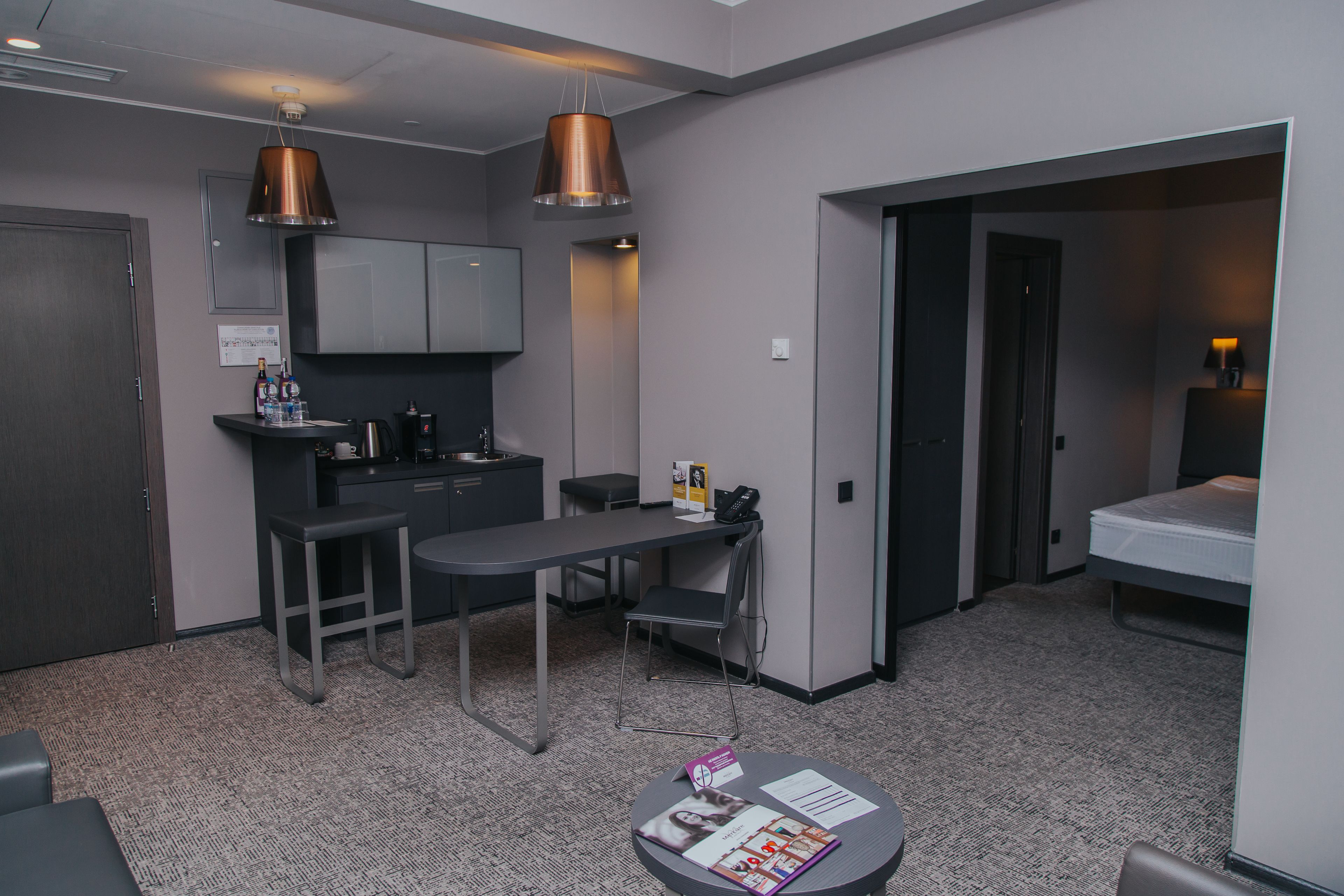 A compact hotel room with a kitchenette, a dining area, and a separate sleeping area.