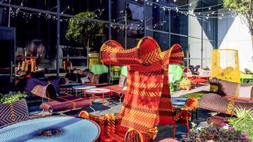 An outdoor seating area with various chairs and tables, some with colorful woven patterns.