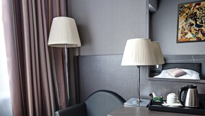 A modern hotel room with a desk, chair, lamp, and a painting on the wall. - Mercure Kyiv Congress (Kyiv)