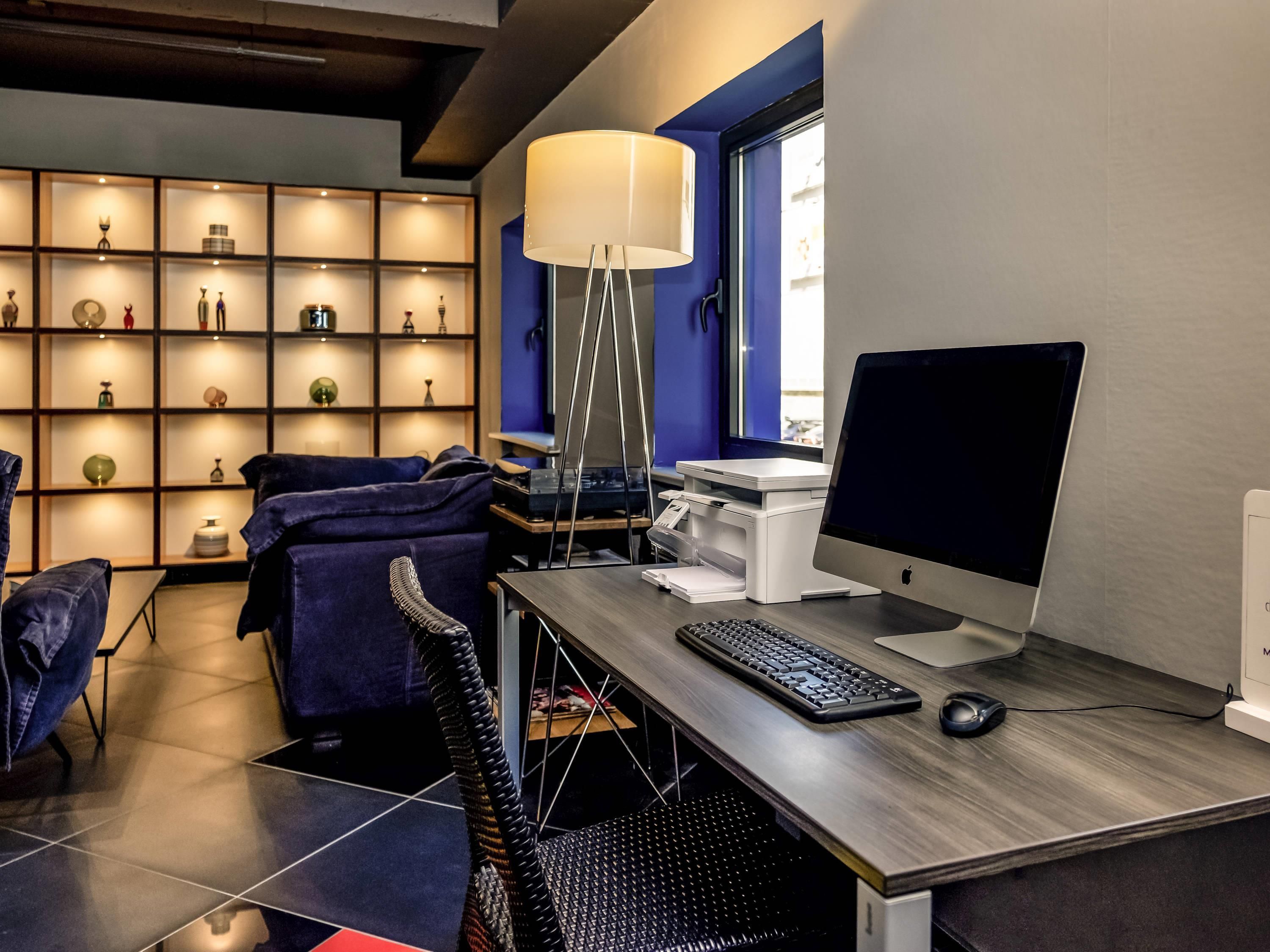 Un espace de bureau moderne comprenant un bureau, un ordinateur et une étagère contenant divers objets.