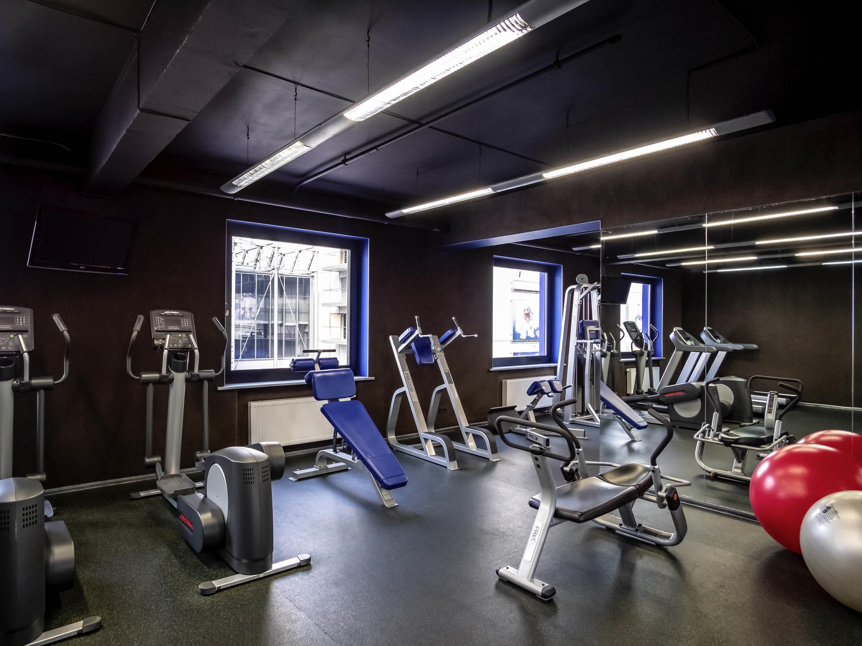 Une salle de sport équipée de matériel d’exercice, dotée de grandes fenêtres et d’un mur entièrement recouvert de miroirs.