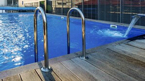 A swimming pool with metal railings and a wooden deck. - Mercure Kyiv Congress (Kyiv)