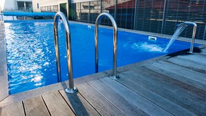 A swimming pool with metal railings and a wooden deck. - Mercure Kyiv Congress (Kyiv)