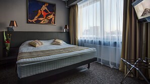 A hotel room with a large bed, a painting on the wall, a TV, and a view of the city through sheer curtains. - Mercure Kyiv Congress (Kyiv)