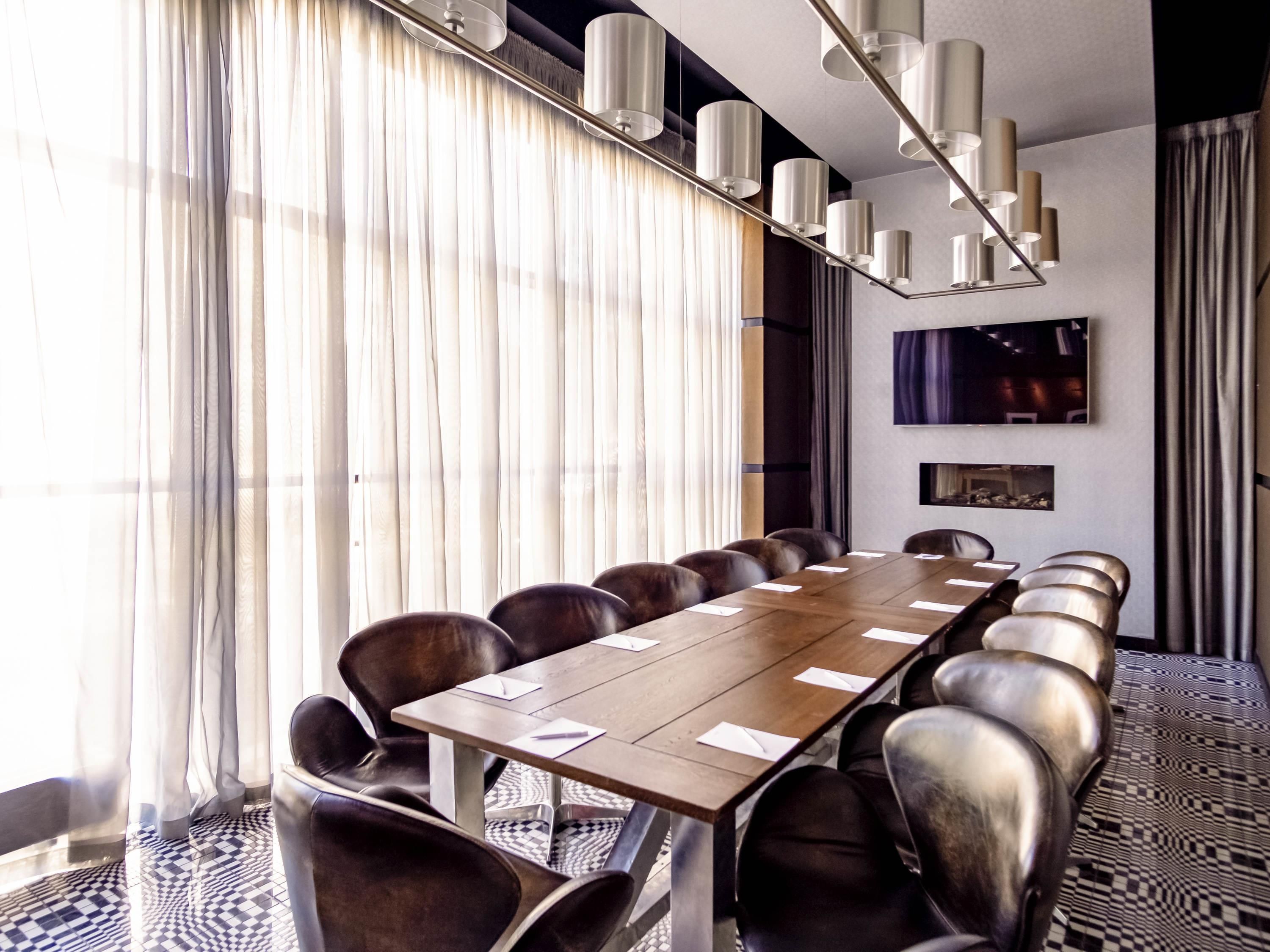 A conference room with a long table, chairs, and a modern chandelier.