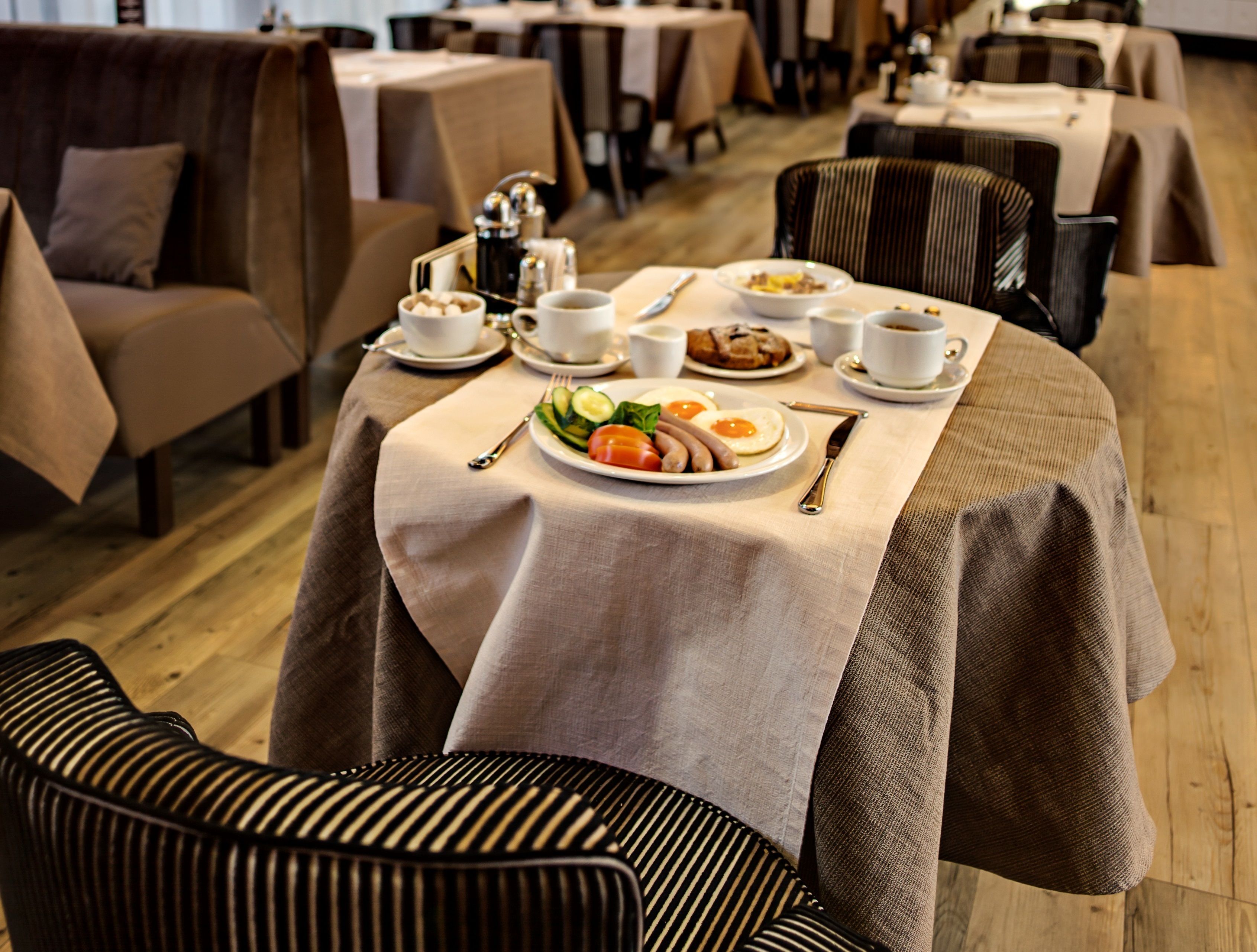 A dining area with tables set for breakfast, including plates of food, cutlery, and cups.
