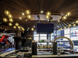 A modern bar with a curved counter, a large TV screen, and a variety of liquor bottles. - Mercure Kyiv Congress (Kyiv)