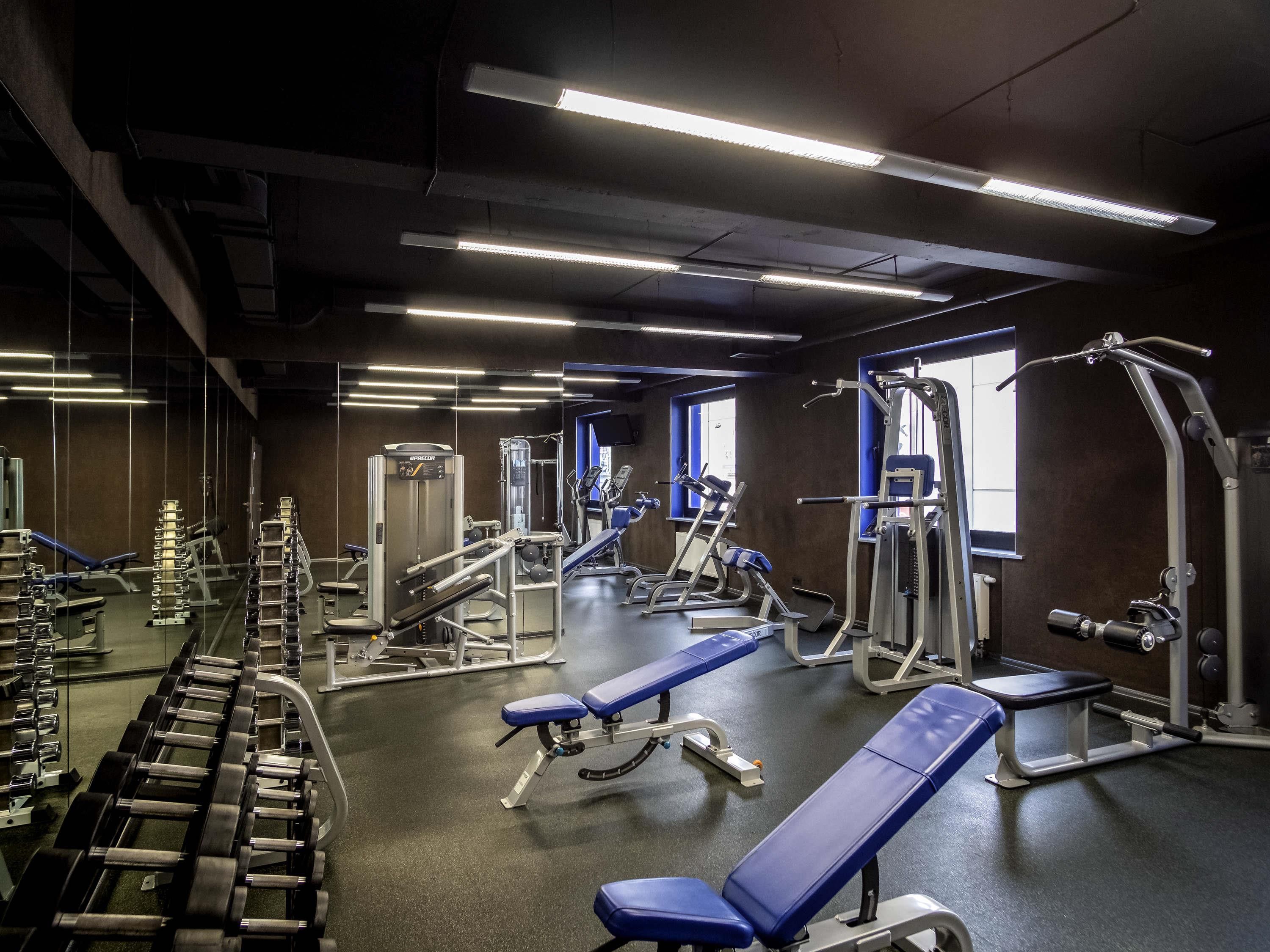 A gym with various exercise equipment, benches, and weight machines.