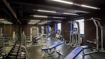 Un gimnasio con varios equipos de ejercicio, bancos y máquinas de pesas.