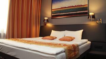 Una habitación de hotel con una cama grande, dos lámparas de noche, un cuadro en la pared y una ventana con cortinas.